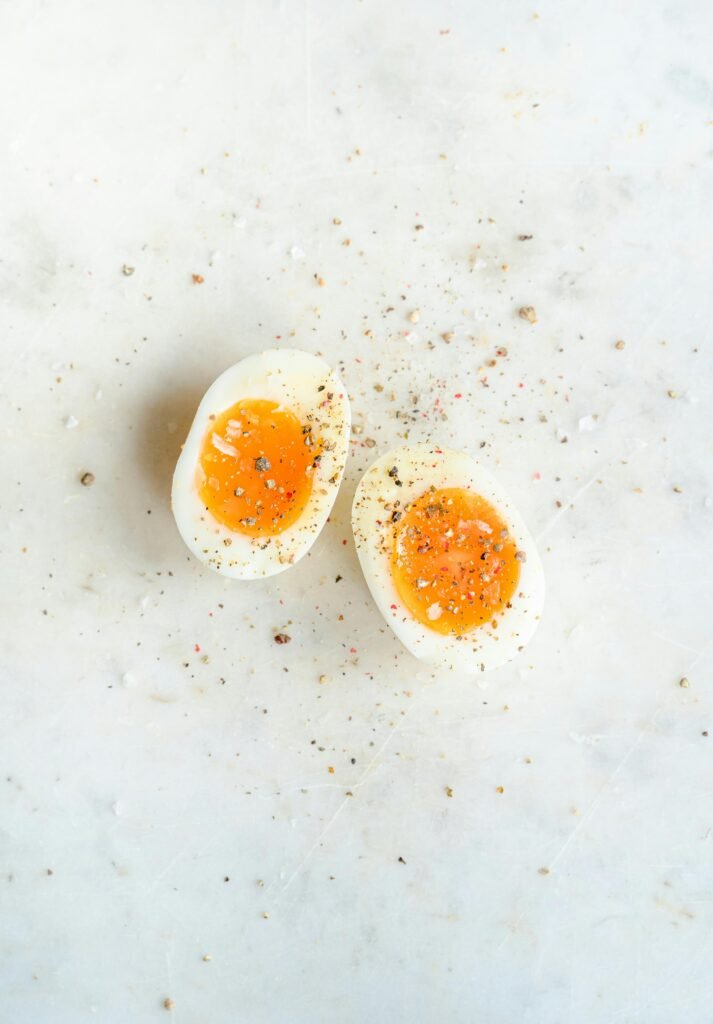 Top view of soft boiled eggs with black pepper seasoning on a marble surface.